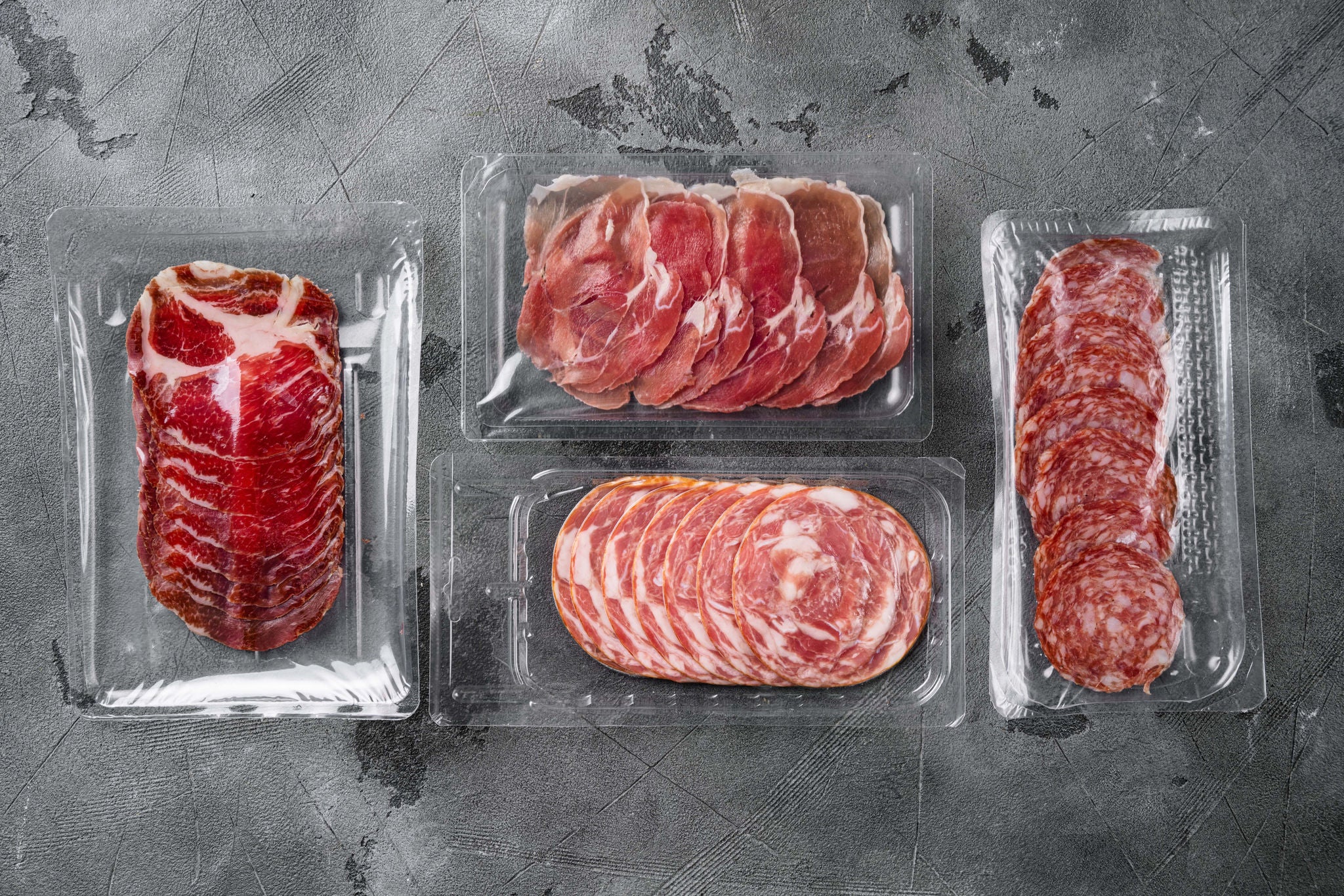 Vacuum packed sausage Prosciutto salami set, on gray stone table background, top view flat lay, with copy space for text; Shutterstock ID 2087296351; purchase_order: MUDE; job: ; client: Cornelia Geiger; other: 